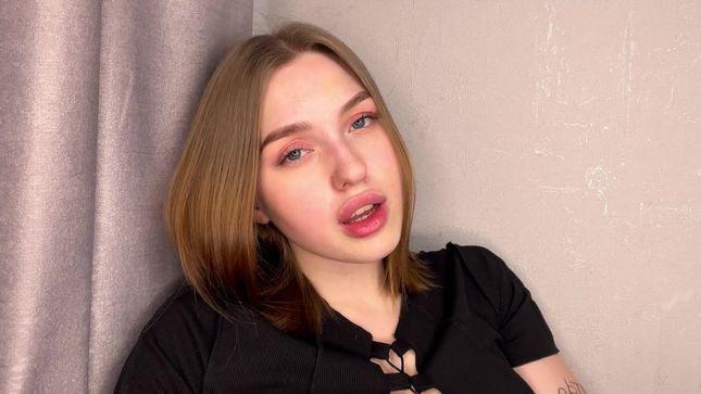 Honey Sasha in a skirt caresses herself with playful fingers